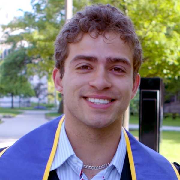 One CWRU student smiling for the camera on Case Quad in their cap and gown.